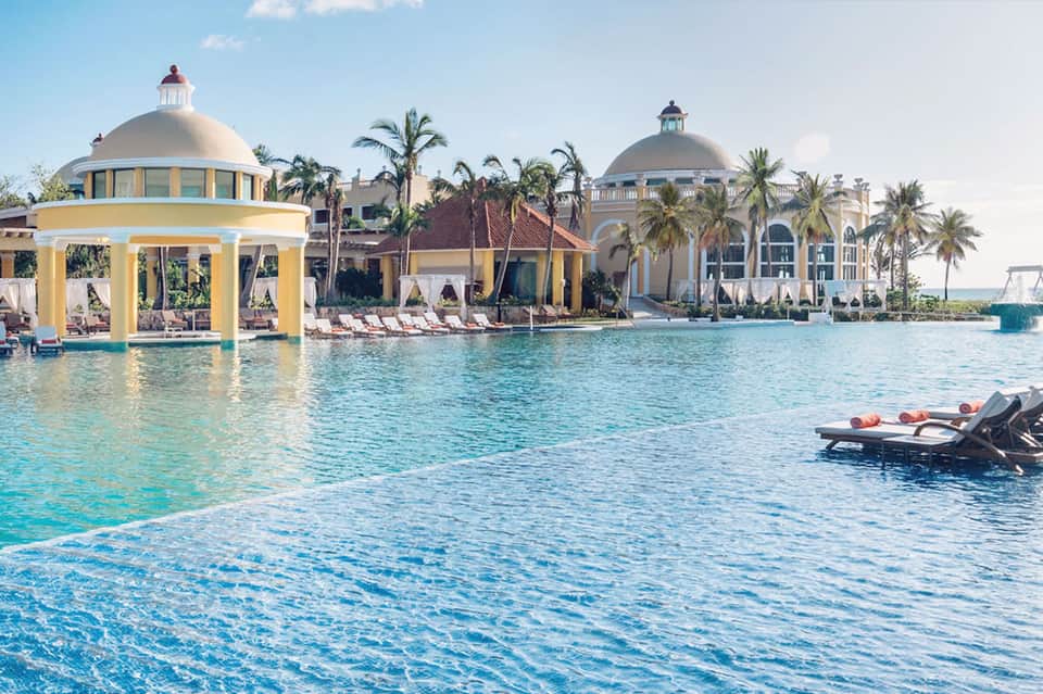 Luxury tropical resort with yellow gazebo, lagoon pools, palm trees, and ornate architecture