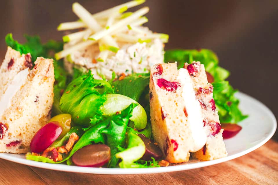 Gourmet sandwich with colorful vegetables and garnishes on a white plate