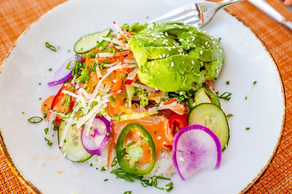 Colorful gourmet salad with avocado, sesame seeds, fresh vegetables on white plate