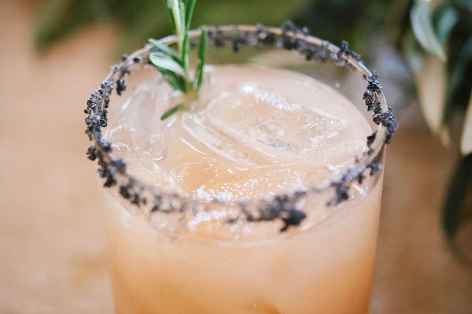 Lavender-rimmed cocktail with fresh rosemary garnish and ice, served in a clear glass