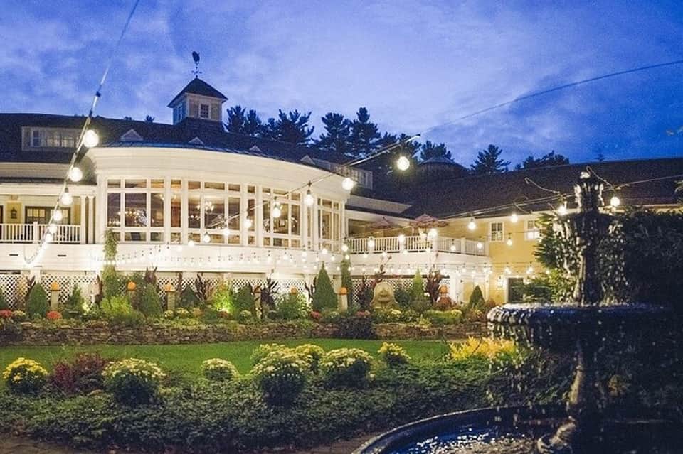 Illuminated resort pavilion with white columns and manicured gardens at dusk