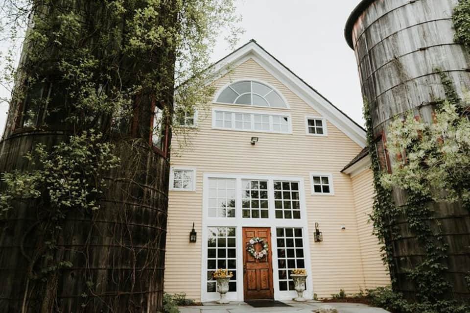 Historic white farmhouse with ivy-covered walls and wooden barn doors