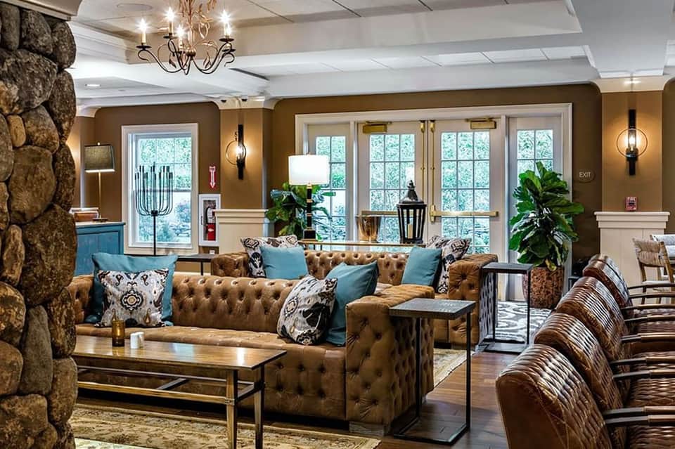 Upscale hotel lobby lounge with brown leather seating, stone fireplace, and blue accents