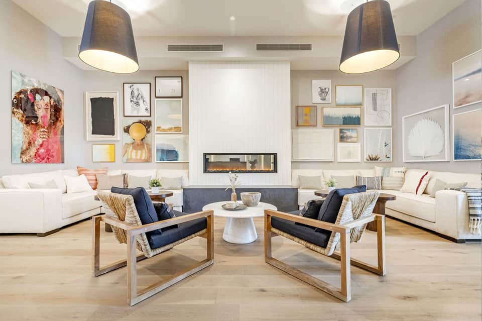 Contemporary living room with white sofas, fireplace, gallery wall art, and wooden accent chairs