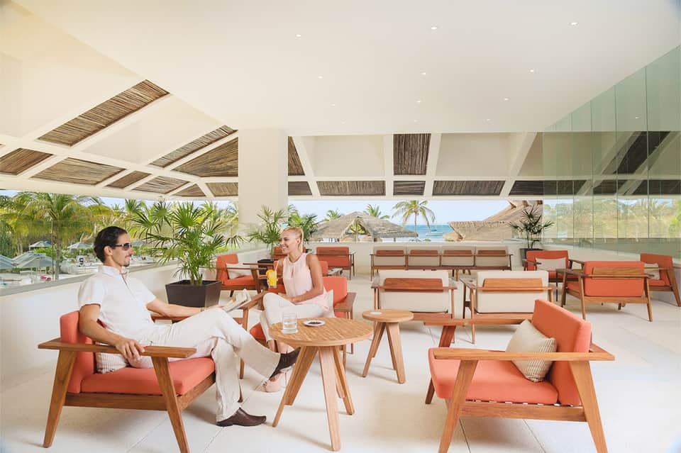 Beachfront lounge with coral chairs, ocean view, and casual seating area