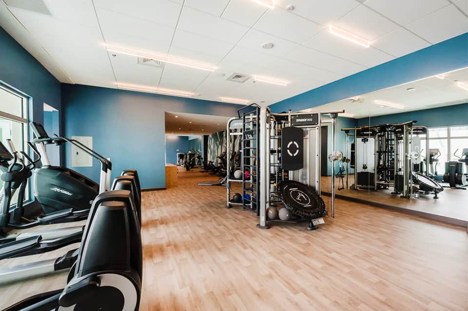 Fitness center with cardio equipment, blue accent walls, and wooden flooring