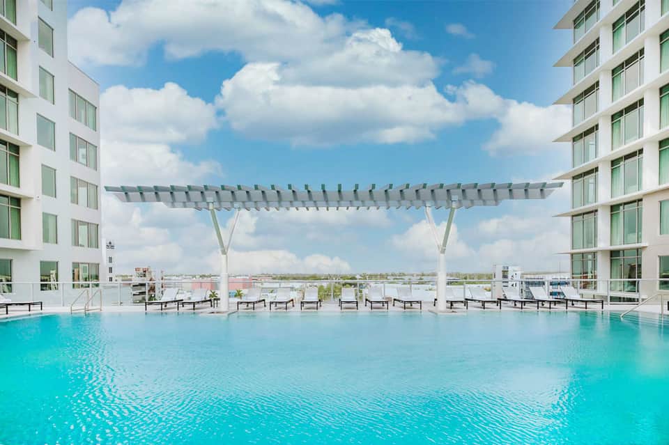 Modern rooftop pool with turquoise water and white pergola shade structures