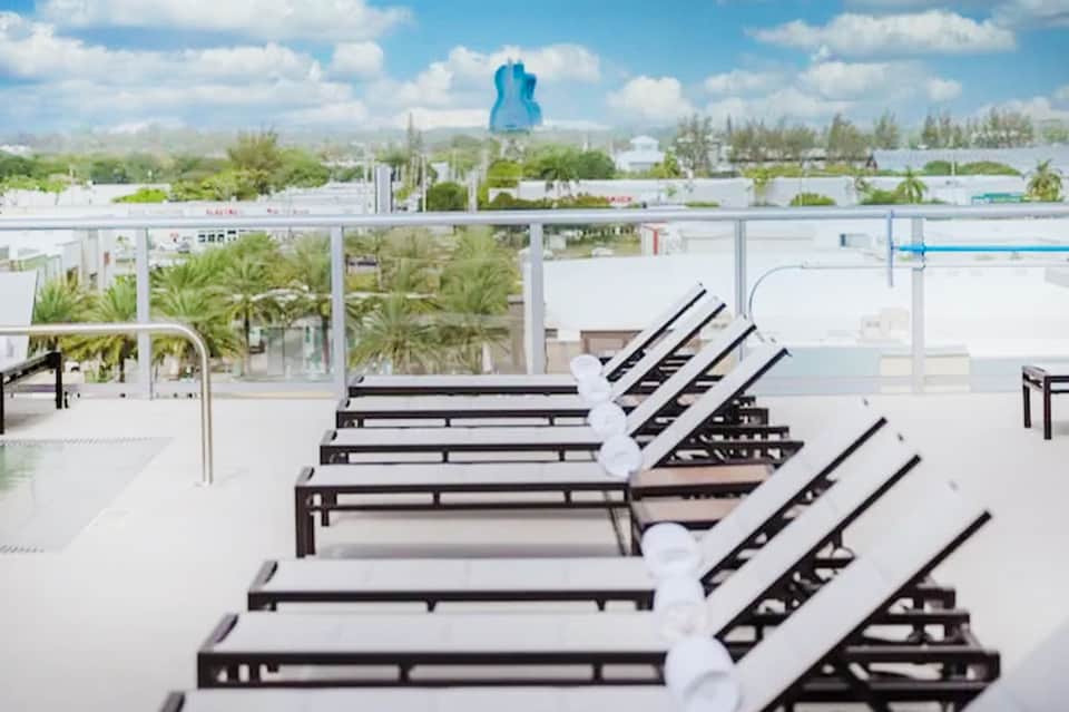 Rooftop lounge chairs overlooking theme park with blue guitar-shaped structure in distance
