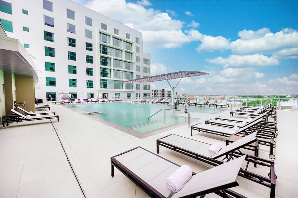 Modern hotel rooftop pool with lounge chairs and architectural shade structure
