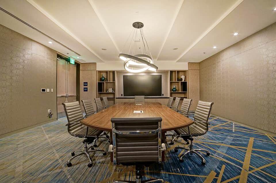 Modern conference room with oval wood table, leather chairs, and large display screen