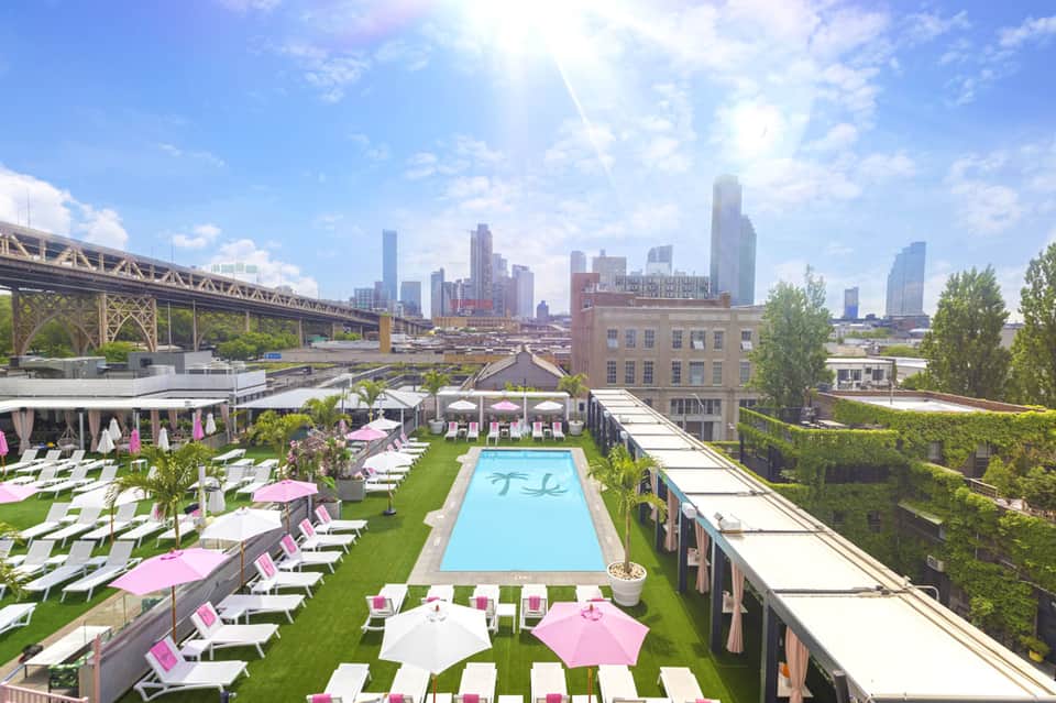 Rooftop pool and lounge area with pink umbrellas overlooking Chicago skyline and bridge