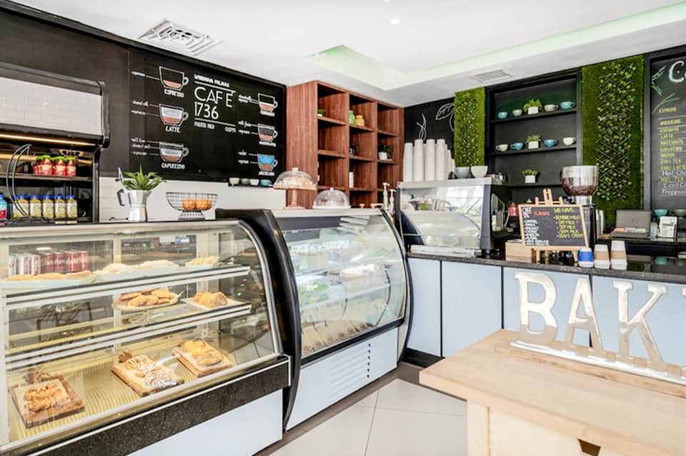 Modern cafe interior with bakery display cases, menu board, and green accents