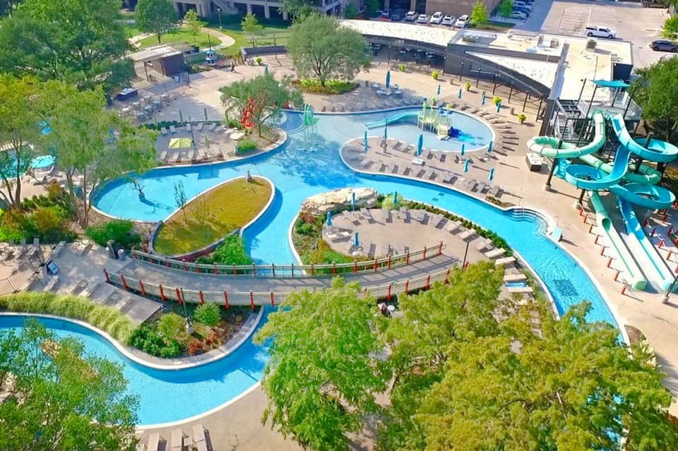 Aerial view of sprawling water park with multiple blue pools, water slides, and surrounding landscaping