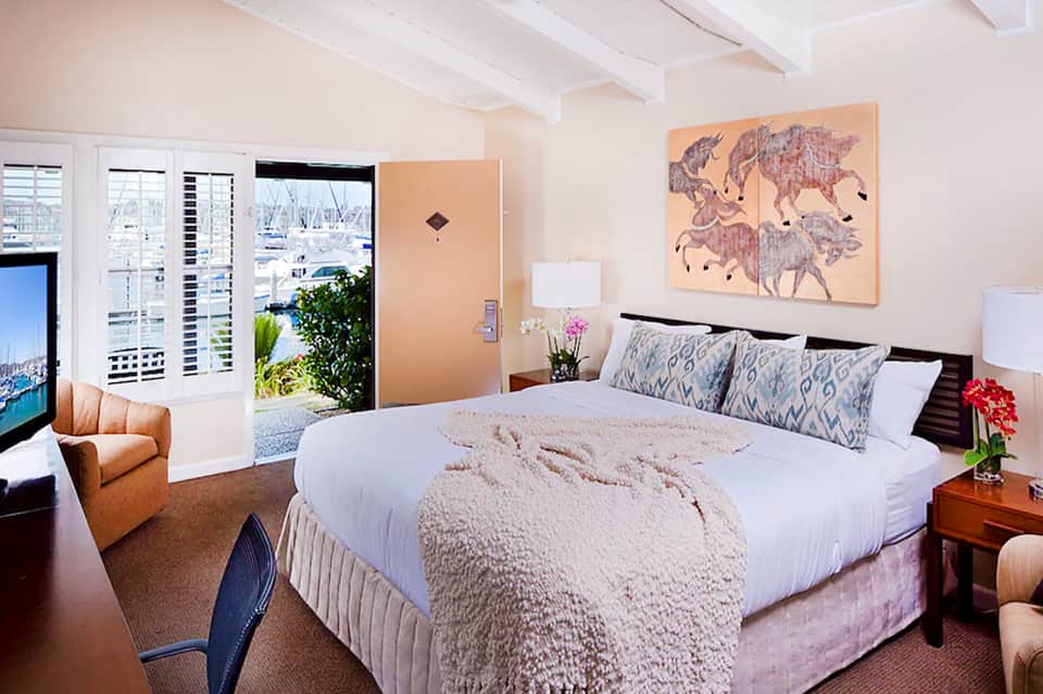 Waterfront hotel bedroom with balcony views, queen bed, and coastal scenery