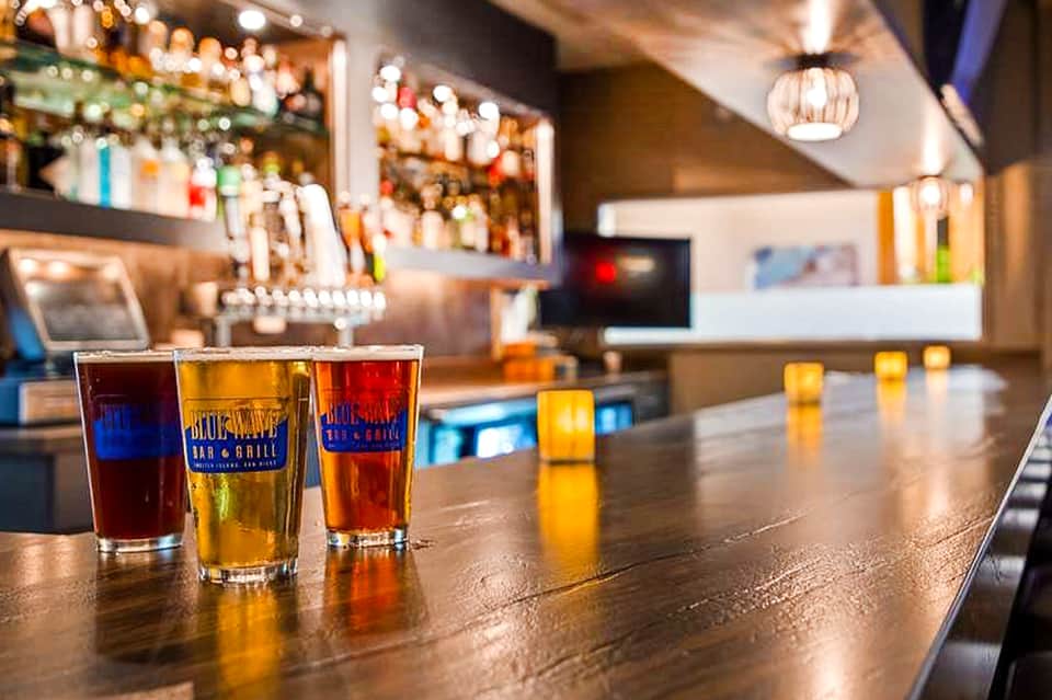 Hotel bar counter with colorful beverages in glasses and stocked shelves with bottles