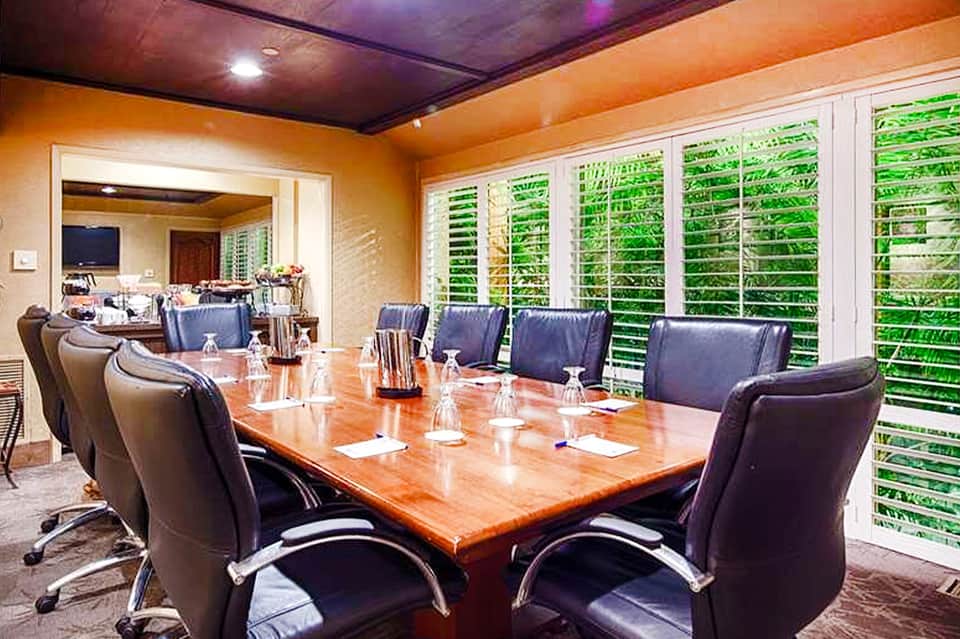 Executive conference room with wood table, leather chairs, and green shutters