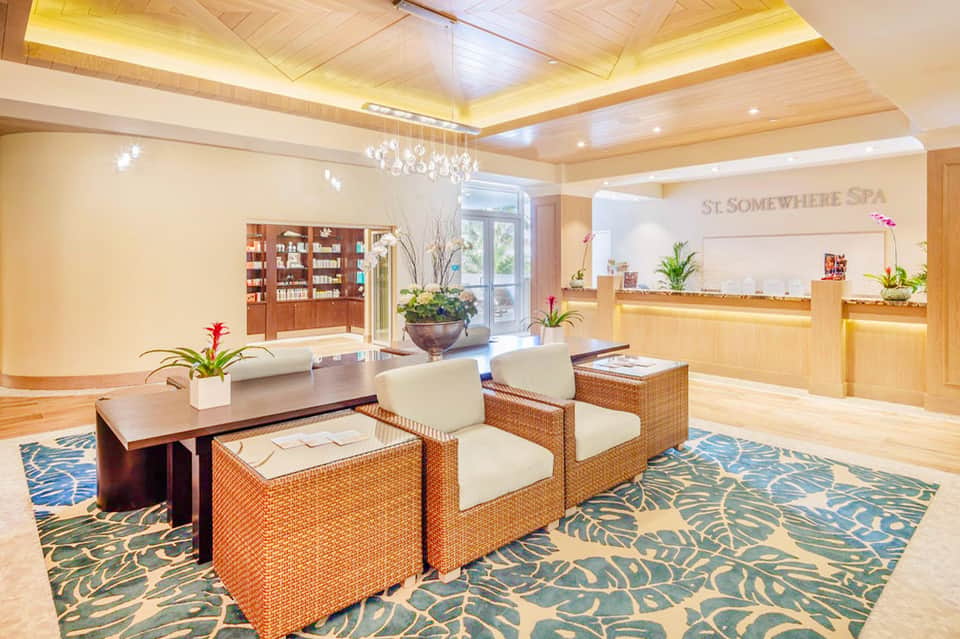 Luxury spa lobby with wooden ceiling, reception desk, leather seating, and tropical plants