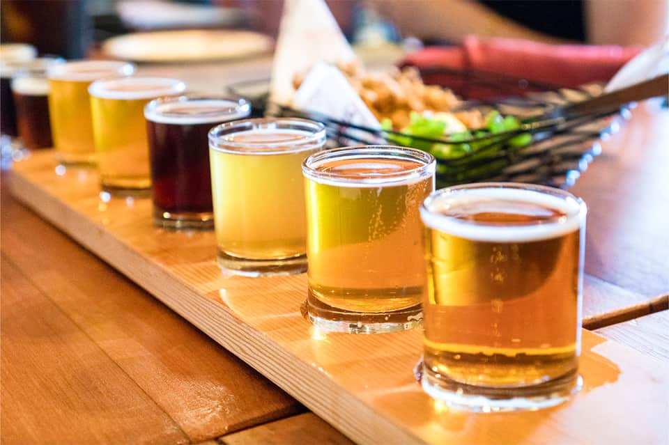 Beer flight tasting board with multiple craft beer glasses on wooden surface
