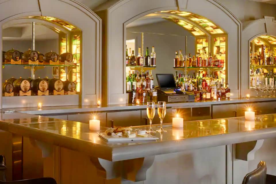 Upscale bar with illuminated glass display cabinets, bottles, and elegant counter seating