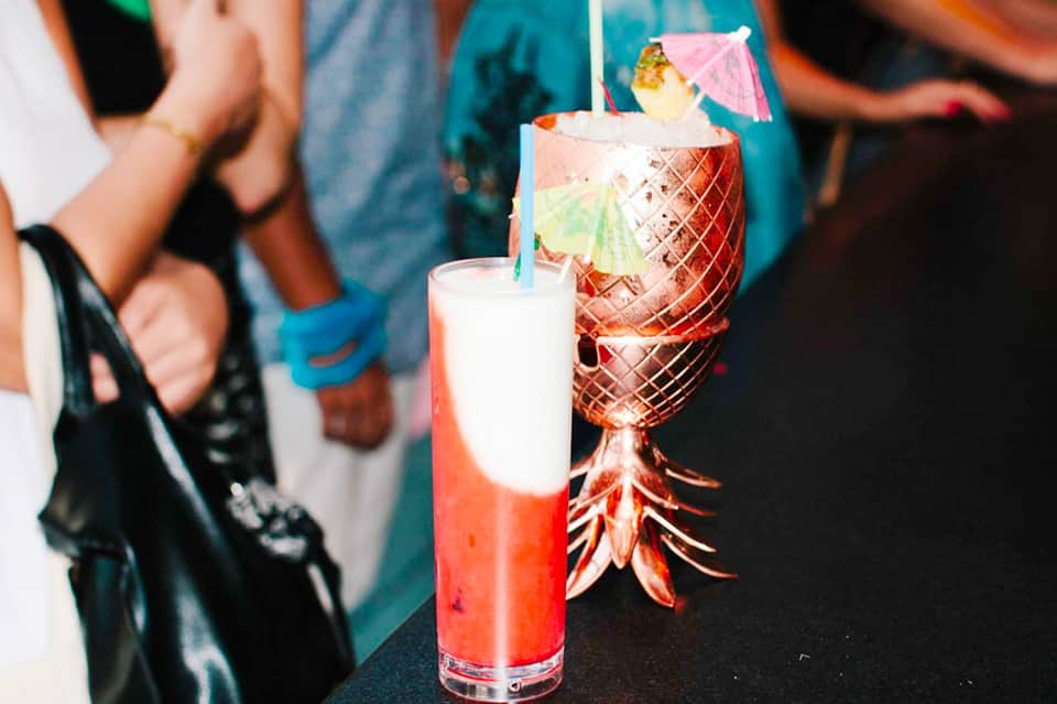 Tropical cocktails with pineapple and umbrella garnish served at beachside bar