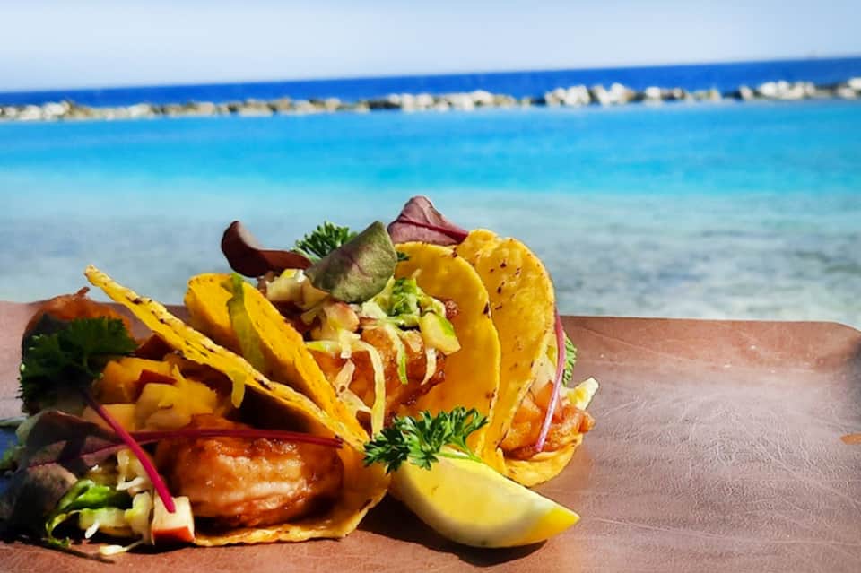 Fish tacos with yellow shells and fresh vegetables served beachside with ocean view
