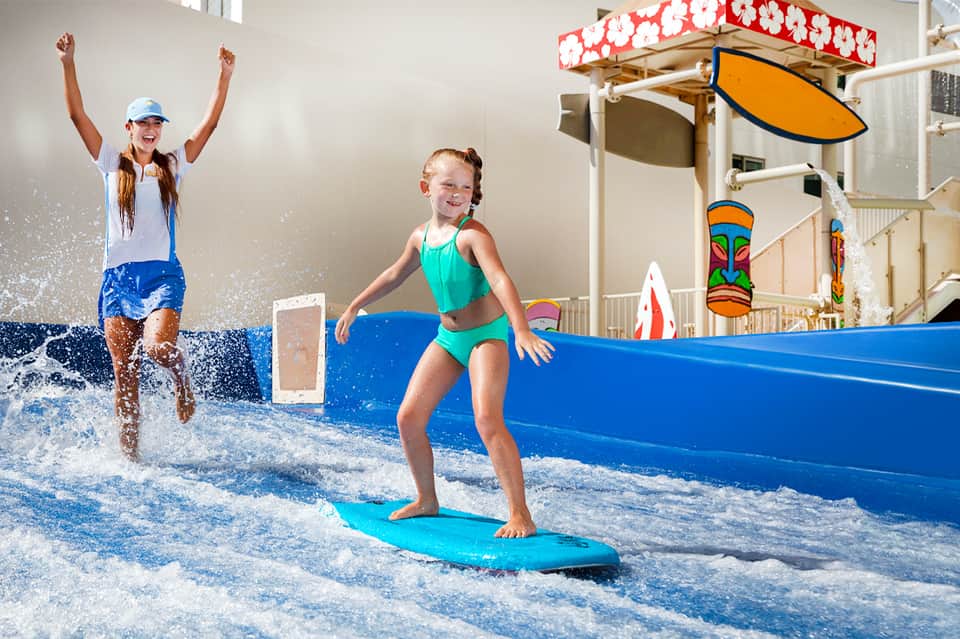 Children learning to surf in indoor wave pool with professional instructor