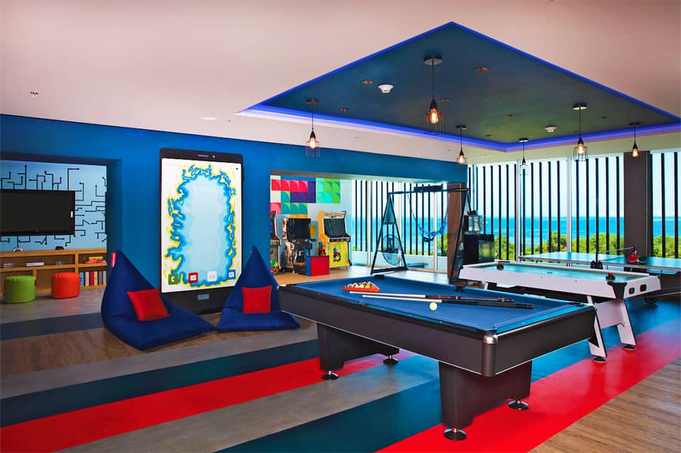 Modern recreation room with blue pool table, gaming area, and ocean view windows