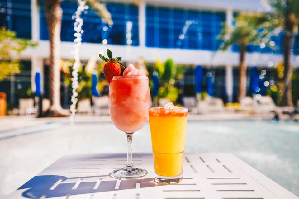 Colorful tropical cocktails with fresh strawberry garnish poolside at resort bar