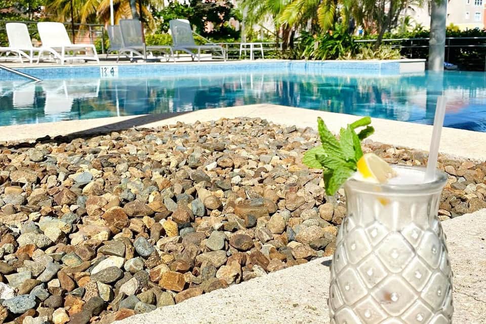 Poolside mojito cocktail with mint and lime overlooking resort pool and palm trees