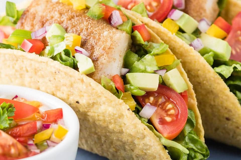 Colorful tacos with fresh vegetables, lettuce, tomatoes, and salsa garnish