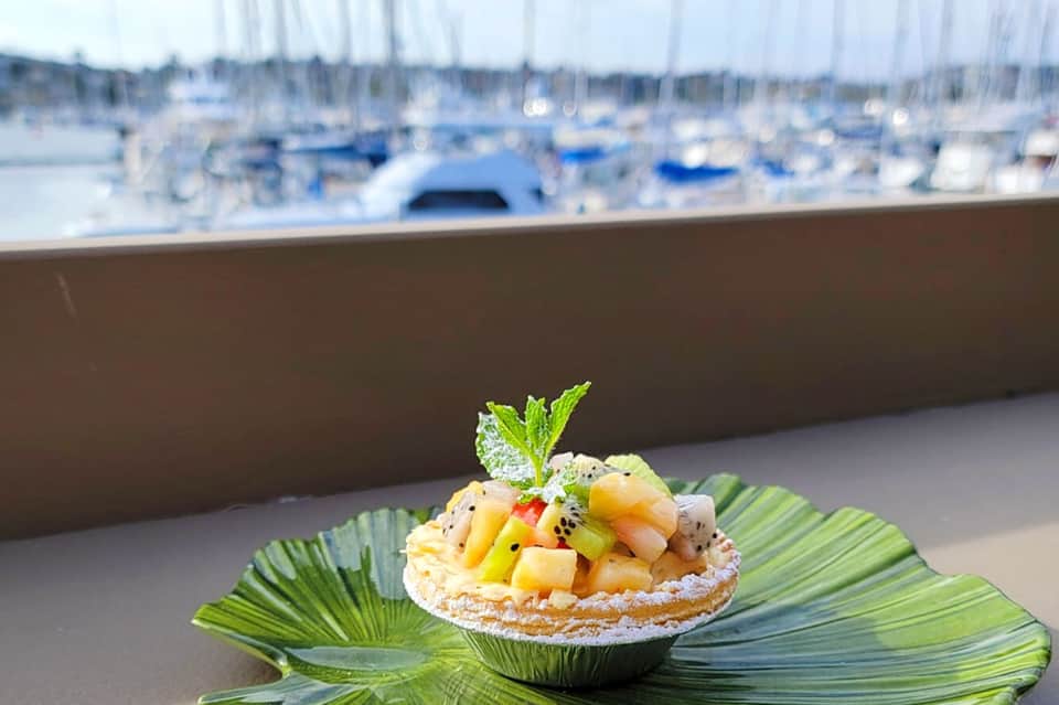 Gourmet ceviche appetizer in seashell dish overlooking marina with sailboats