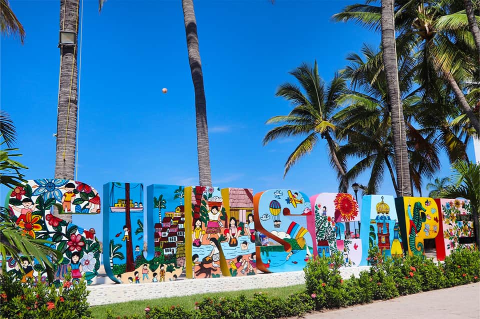 Colorful beachside mural art installation with palm trees under bright blue sky