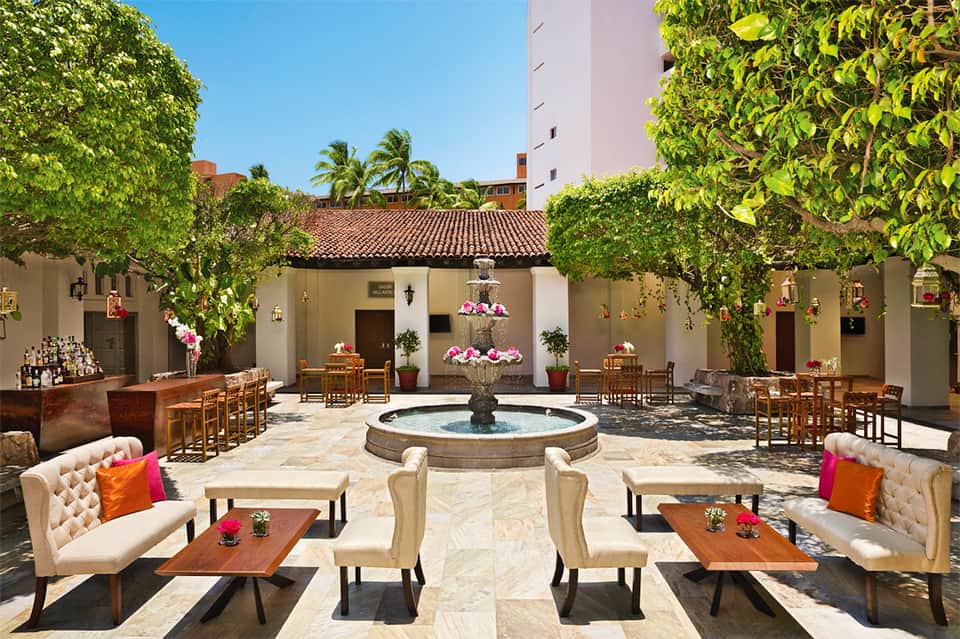Elegant hacienda-style courtyard with central fountain, seating areas, and flowering vines