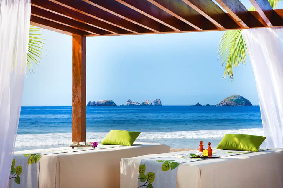 Oceanfront lounge area with white pergola, cushions, and island views