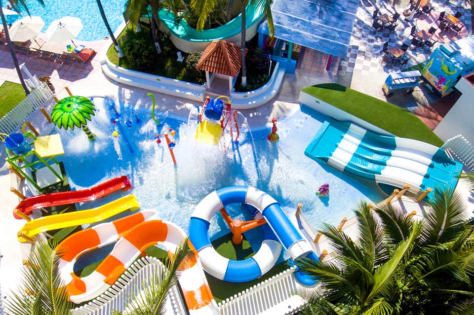Aerial view of colorful waterpark with slides, splash pools, and palm tree landscaping