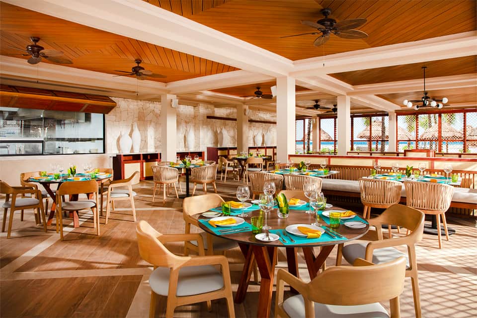 Modern dining room with wooden ceiling, colorful table settings, and ocean views