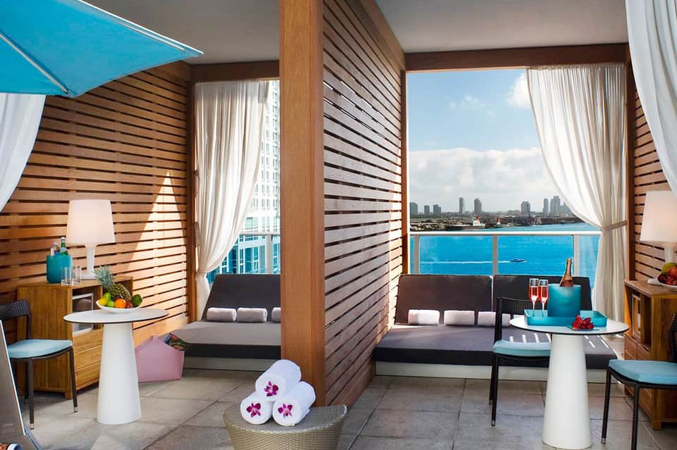Luxury hotel suite balcony with ocean and city skyline views, modern furnishings