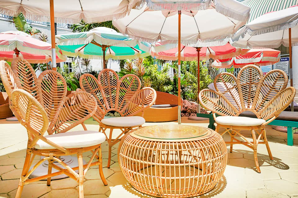Outdoor lounge seating with woven rattan chairs under colorful umbrellas and shade structures