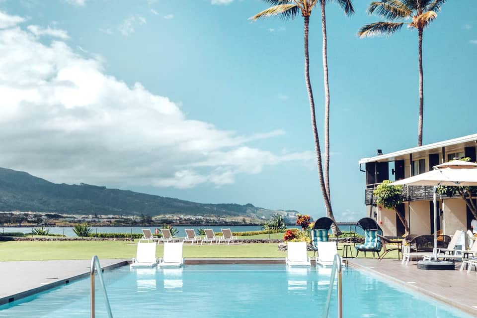 Modern oceanfront pool with mountain backdrop, palm trees, and contemporary resort architecture