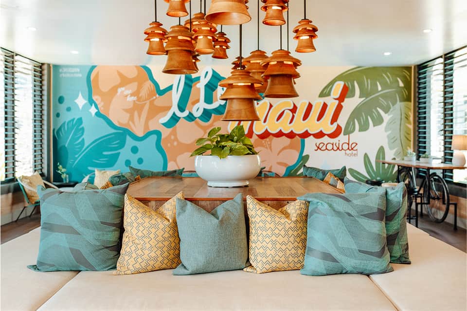 Colorful hotel lobby with turquoise mural, hanging copper bell lights, and seating area