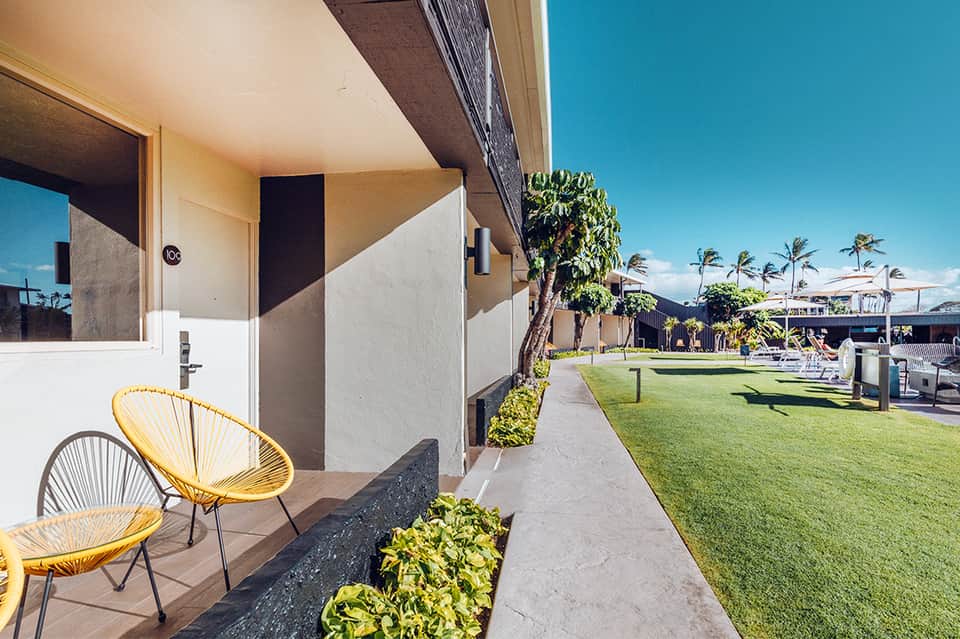 Modern hotel room with yellow chairs, green lawn, and bright sunny day