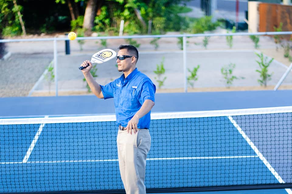 Tennis instructor holding a paddle on a blue court