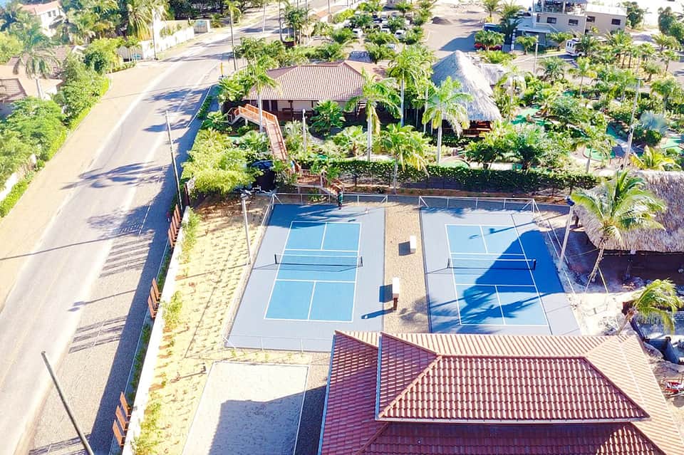 Aerial view of tennis courts surrounded by lush tropical landscaping and palm trees