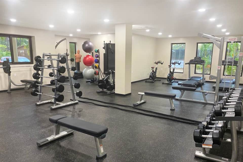 Full-service fitness center with weight racks, dumbbells, bikes, and exercise equipment