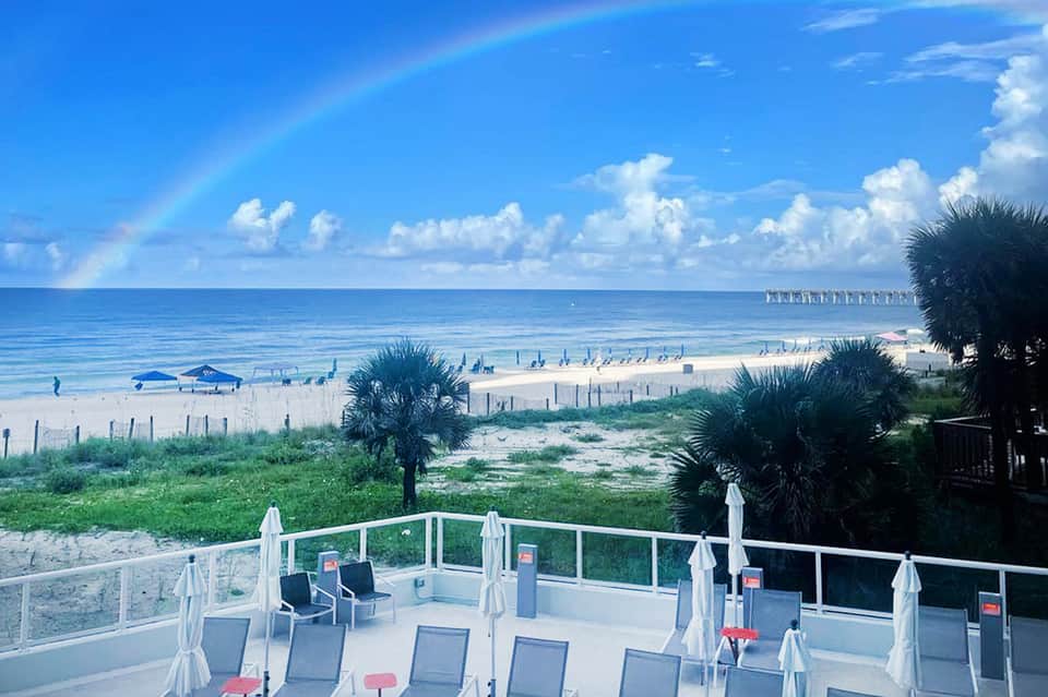 Beachfront terrace with lounge chairs and umbrellas overlooking sandy beach and ocean pier