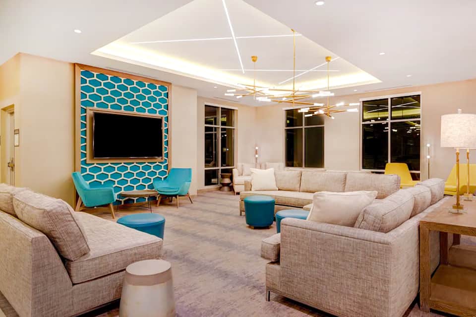 Modern resort lobby lounge with teal accent wall, comfortable seating, and geometric ceiling design