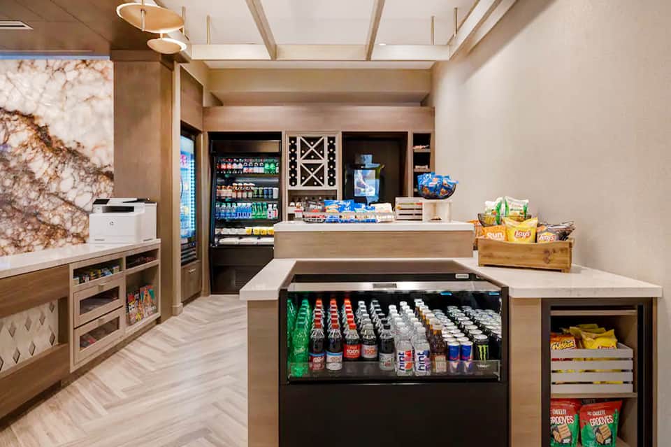Modern resort snack bar with beverage coolers, vending displays, and wood cabinetry