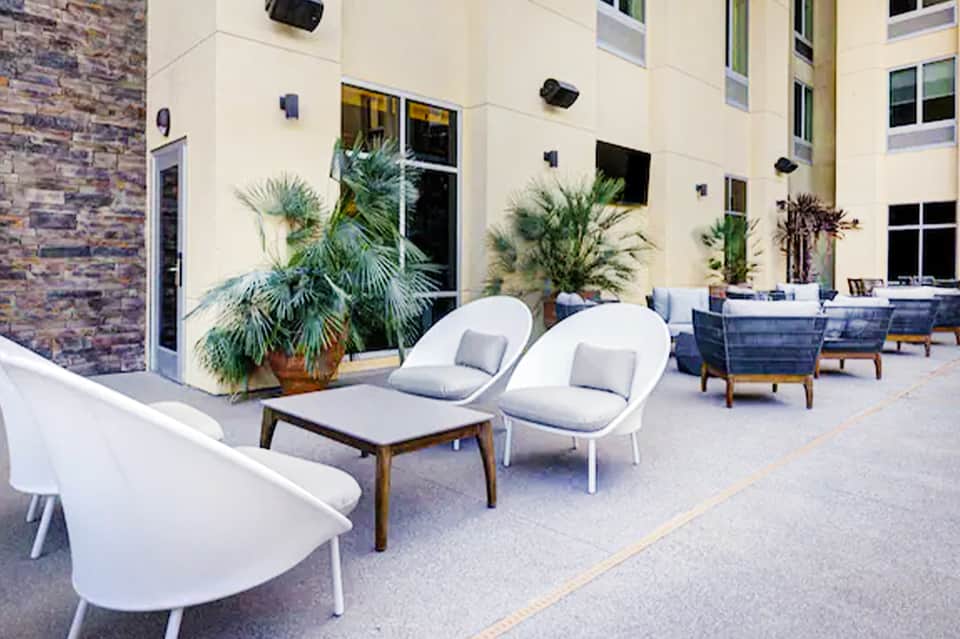 Contemporary courtyard with white modern chairs, potted palm plants, and minimalist furniture arrangement