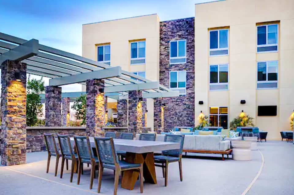 Contemporary resort courtyard with stone fire pits, modern table settings, and illuminated building facade
