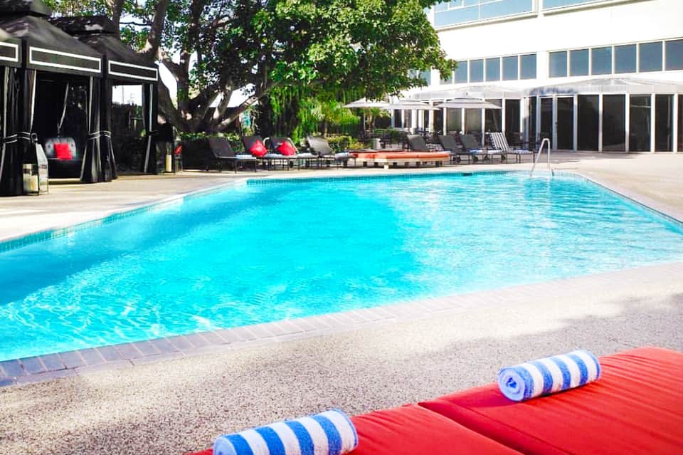 Contemporary hotel pool with turquoise water, lounge chairs, black cabanas, and modern building